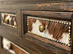 an old wooden dresser with metal knobs and cow hide pattern on the drawer handles