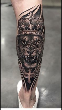 a man's leg with a lion wearing a crown and cross tattoo on it