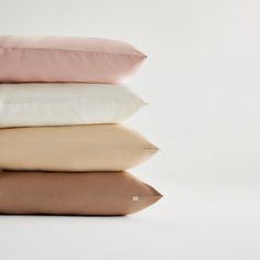 four pillows stacked on top of each other in different colors and sizes, with one folded down