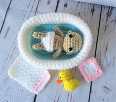 two crocheted animals laying in a bowl next to a rubber duck