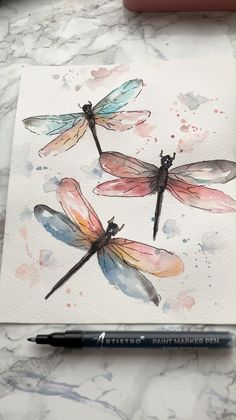 three watercolor dragonflys sitting on top of a piece of paper