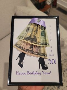 a person holding up a birthday card with money on it