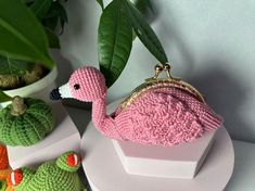 a crocheted pink flamingo purse sitting on top of a white table next to other small green plants