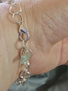 This Watermelon Falls silver-plated charm bracelet has been constructed from split rings to allow more durability as well as ability to add charms that do not have open jump rings.  The length of chainmail is approximately 8 inches (as shown in photo) not including the clasp and included charm. It has a lobster claw clasp and a small fluorospar/fluorite end charm. For smaller wrists, it will have a larger "tail." Fluospar/fluorite charm color may vary.  Watermelon Falls is designed and created by A Slice of Southern Illinois. Each charm bracelet comes in its own box. The additional charms photographed are for example only. Silver Link Jewelry With Charms, Metal Bracelets With Jump Ring For Jewelry Making, Silver Metal Bracelets With Extender, Sterling Silver Bracelet With Extender, Silver Metal Bracelets With Lobster Clasp, Adjustable Link Charm Bracelet In Sterling Silver, Adjustable Link Sterling Silver Charm Bracelet, Metal Link Bracelets With Jump Ring, Adjustable Sterling Silver Link Charm Bracelet