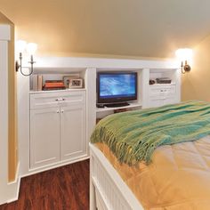 a bedroom with a bed, television and cabinets