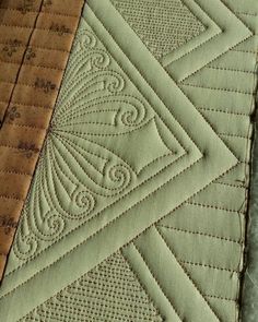 two quilts that are next to each other on a table top, one is green and the other is brown