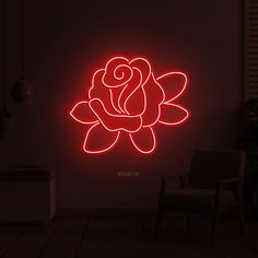 a red rose on a dark wall in a room with a chair and lamp next to it