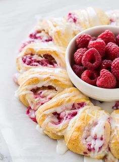 raspberry rolls with icing and fresh raspberries in a bowl