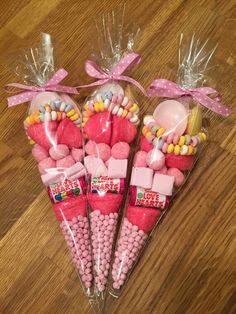 three candy cones with candies in them on a wooden floor next to some bags