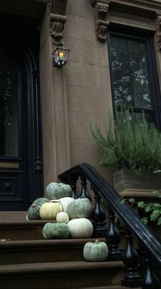 pumpkins and gourds are sitting on the steps in front of a building