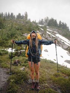 a woman standing on top of a snow covered mountain holding two ski poles in her hands