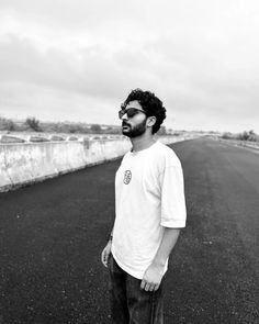 a man standing in the middle of an empty road with his hand on his hip