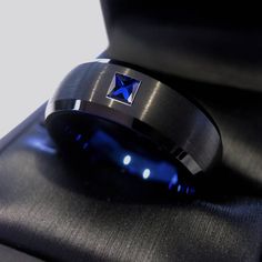 a blue diamond ring sitting on top of a black box