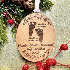 a wooden ornament with a baby's footprints on it next to christmas decorations