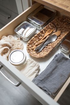 an open drawer with utensils and other kitchen items in it on top of a counter