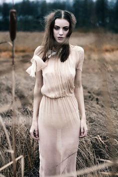 a woman standing in tall grass wearing a dress