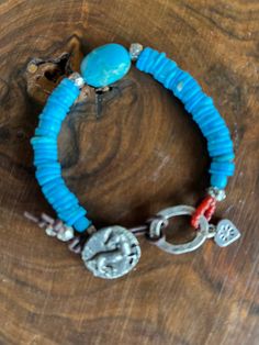 This detailed horse / pony button looks so pretty against these brilliant blue turquoise stones. The center stone is blue turquoise magnesite. The pony button, with the pony in raised relief, is pewter that has been finished to look like oxidized Sterling Silver. All the other silver in this bracelet is .925 Sterling. The loop has hand stamped designs and the sterling heart charm has a tiny hallmark on its reverse side. 7 and 1/2 inches long. Rustic Handmade Blue Beaded Bracelets, Handmade Western Style Turquoise Bracelet, Handmade Western Turquoise Bracelet, Handmade Western Turquoise Bracelets, Rustic Blue Adjustable Bracelets, Rustic Adjustable Blue Bracelets, Rustic Blue Adjustable Beaded Bracelets, Rustic Blue Adjustable Beaded Bracelet, Rustic Adjustable Blue Beaded Bracelet