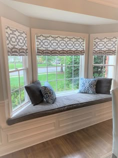 a window seat in the corner of a room with two pillows on top of it