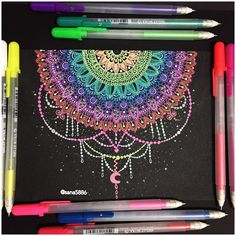 some markers and pens are laying on top of a black paper with an intricate design