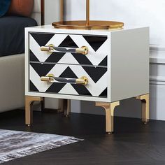 a black and white cabinet with gold handles in a living room next to a bed