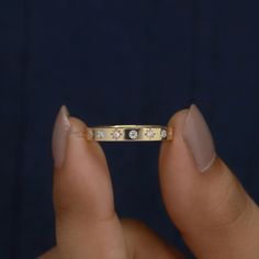 a woman's hand holding a gold ring with three diamonds on the middle and sides