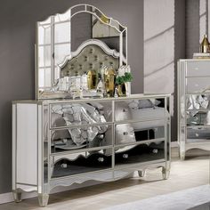 a bedroom scene with focus on the bed and mirrored dresser in the foreground,