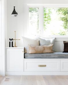 a white window seat with pillows on it