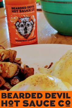 an egg and potatoes on a white plate with a bottle of hot sauce in the background