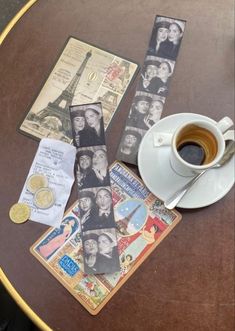 a cup of coffee sitting on top of a table next to some cards and coins