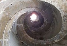 the inside of a concrete structure with a light at the end