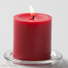 a red candle sitting on top of a glass plate