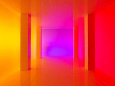 an empty room with bright colored walls and flooring in the center is lit by brightly colored lights