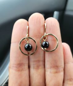 LIGHTWEIGHT | MODERN Add a perfect finish to your style with these lightweight dangling earrings (BLACK ONYX). These studs are CHIC and MODERN These black Onyx gemstones will also make a perfect tenth anniversary gift.  The Gold filled circles are hammered and a small drop of Black Onyx ball is attached and suspended to a small gold filled ear wire. DETAILS: Black Onyx SIZE: 6 mm  The Gold Filled Circle component is 16 mm (1.6 cms) MATERIAL: 14/20 Gold Filled Have some questions? Feel free to as Elegant Single Open Circle Earring, Elegant Round Pendant Earrings With Ear Wire, Minimalist Open Circle Jewelry With Matching Earrings, Elegant Open Circle Earrings With Ear Wire, Minimalist Gemstone Hoop Jewelry, Modern Black Hoop Jewelry, Modern Black Round Hoop Earrings, Black Minimalist Sterling Silver Hoop Earrings, Elegant Open Circle Earrings For Everyday