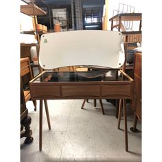 a wooden desk with a glass top in a room filled with shelves and other furniture