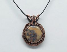 This beautiful pendant is a one of a kind. It is by far one of my favorite pieces. The way the stone in the center stands out makes it fit for a queen and will definitely please! It will stand out in any crowd and makes the perfect gift for birthdays, anniversary, holidays and any occasion! Usually ships in 2-3 days. Handmade Earthy Pendant Jewelry, Earthy Bronze Jewelry Gift, Wire Wrapped Round Pendant Amulet Jewelry, Wire Wrapped Round Pendant Amulet, Bronze Pendant Jewelry With Natural Stones, Handmade Bronze Agate Jewelry, Elegant Oval Pendant Copper Jewelry, Nature-inspired Jewelry With Large Round Pendant, Elegant Copper Oval Pendant Jewelry