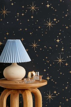 a table with a lamp on it next to a night sky wallpaper