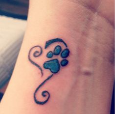 a small tattoo on the wrist of a woman's left arm with a dog paw and heart