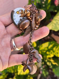 a person holding an antique clock and seashell charm