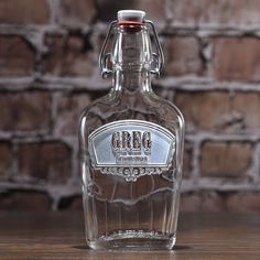 a glass bottle sitting on top of a wooden table next to a brick wall in the background