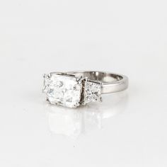 This three-stone diamond engagement ring has a 4.15ct GIA-Certified F color, SI1 clarity radiant-cut center diamond. The two side diamonds weigh 1.25 carats total weight, and are trapezoid-cut. Gia Certified Trillion Cut Diamond Ring For Formal Occasions, Gia Certified Trillion Cut Diamond Ring For Formal Events, Formal Platinum Rings With Trillion Cut, Timeless Square Cut Cubic Zirconia Wedding Ring, Gia Certified Square Cut Sapphire Ring For Formal Occasions, Wedding Square-cut Platinum Diamond Ring, Wedding Square Cut Platinum Diamond Ring, White Gold Sapphire Ring With Square Cut, Square Cut Platinum Wedding Diamond Ring