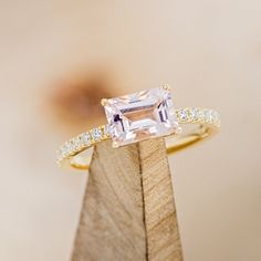 an engagement ring with a pink diamond in the center on top of a wooden stand