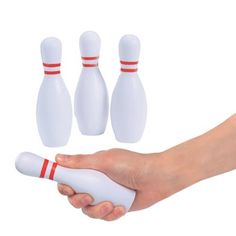 a hand holding a white bowling ball and three pins in the shape of skittles