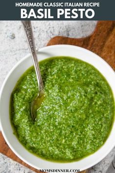 a bowl filled with pesto on top of a cutting board next to a spoon