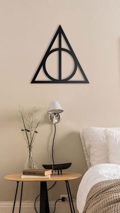 a bedroom with a bed, desk and harry potter symbol wall hanging on the wall