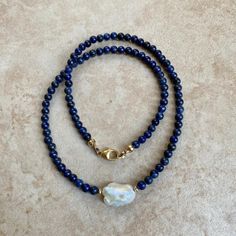 Lapis Lazuli necklace with a freshwater baroque pearl center . Length 16" Lapis is one of the oldest spiritual stones known to man, used by healers, priests and royalty, for power, wisdom and to stimulate psychic abilities and inner vision. It represents universal truth. Throat Chakra. -This information is intended for spiritual support only- Findings 14K GF Beads 4mm FWP 14 x 12mm Lapis Necklace, Lapis Lazuli Necklace, Throat Chakra, Psychic Abilities, Baroque Pearls, Psychic, Lapis Lazuli, Chakra, Cross Necklace