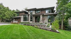 a large house with lots of windows and grass in the front yard, surrounded by trees