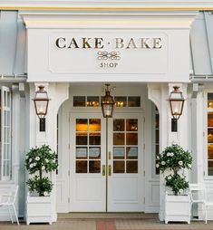 the front entrance to cake bake shop with potted plants and two white chairs