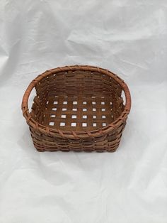 a brown basket sitting on top of a white sheet