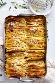 a casserole dish filled with potatoes and parmesan cheese on the side