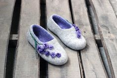 a pair of slippers with purple flowers on them sitting on a wooden bench outside